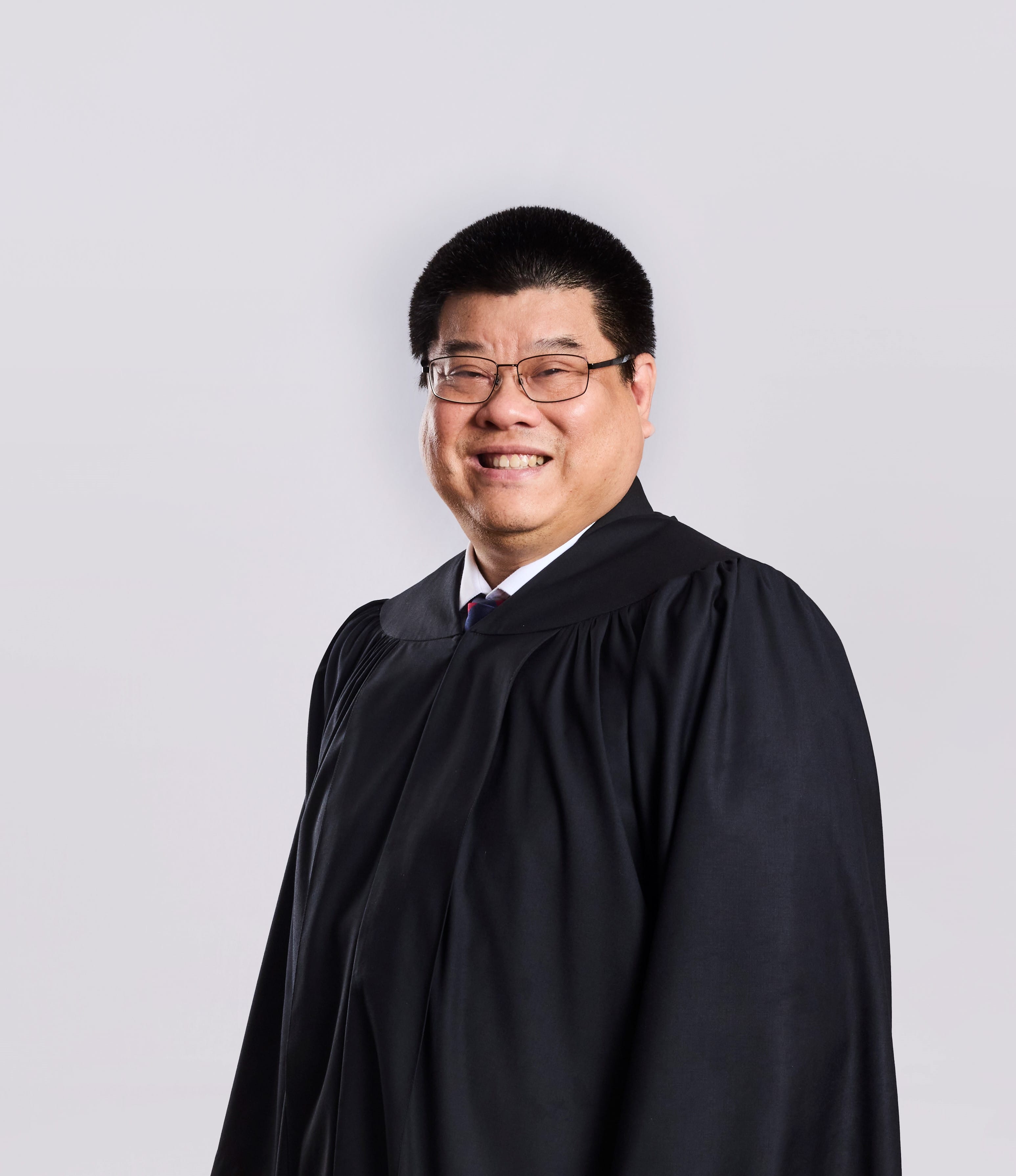 Person in black judicial robe, smiling, wearing glasses.
